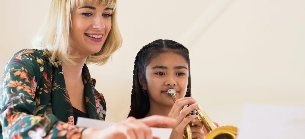 Trumpet teacher teaching a trumpet student a music lesson