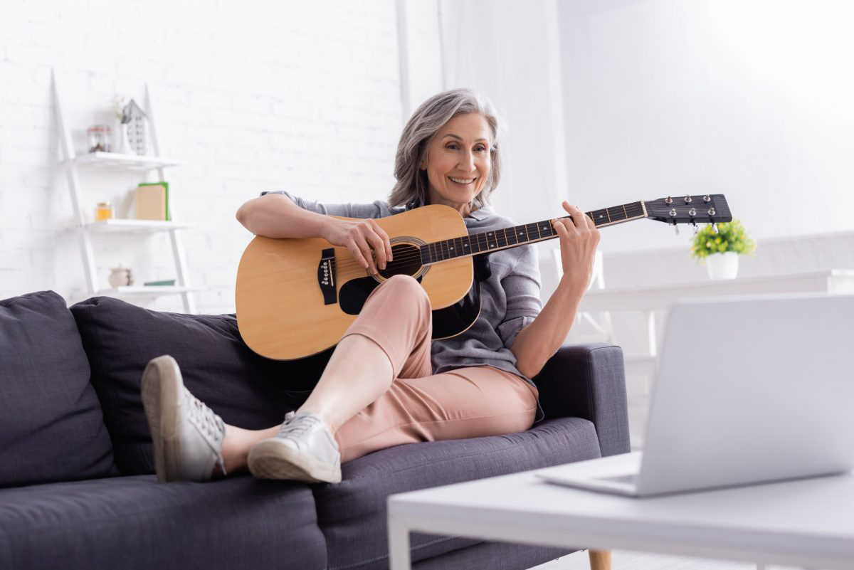 A mature woman enjoys an online guitar lesson.